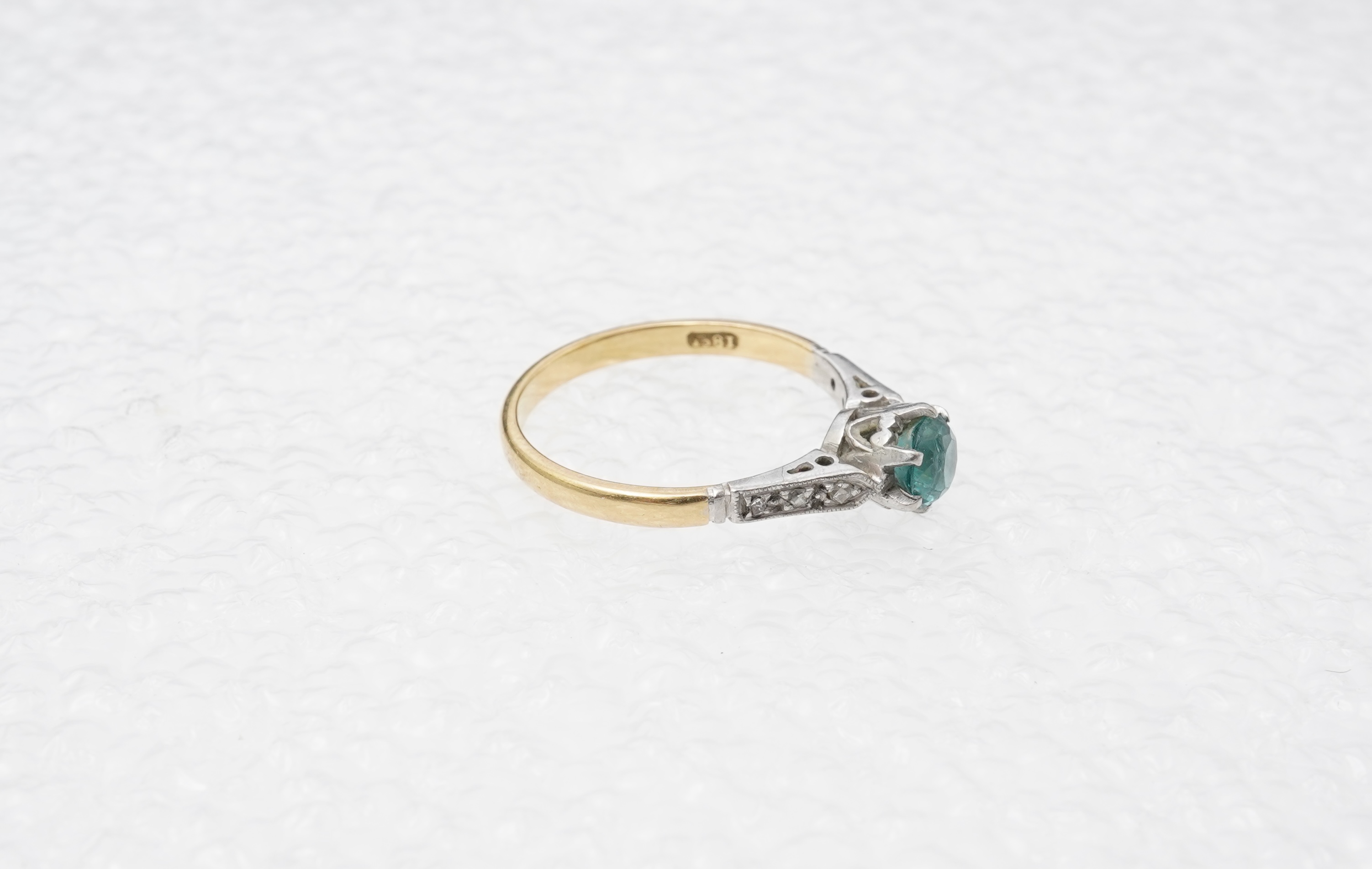 A zircon and diamond ring, mid 20th century, claw-set with a brilliant-cut blue zircon measuring approximately 5mm diameter, to shoulders set with rose-cut diamonds, mounted in gold, size N, stamped 18CT, gross weight ap